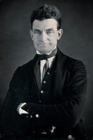 A photograph of John Brown. He is wearing a suit and has his arms crossed.